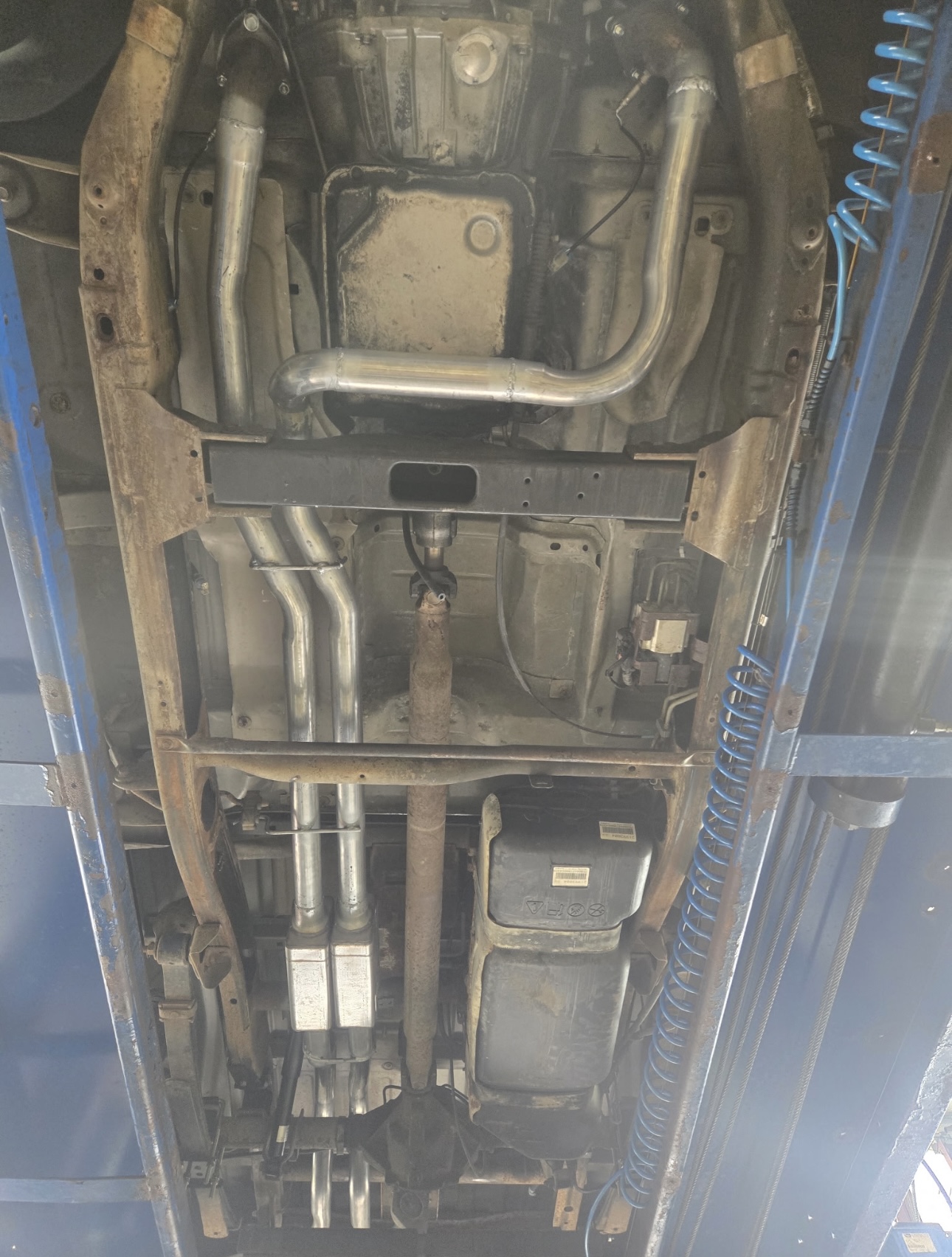Vehicle underbody showing exhaust and chassis work on the lift