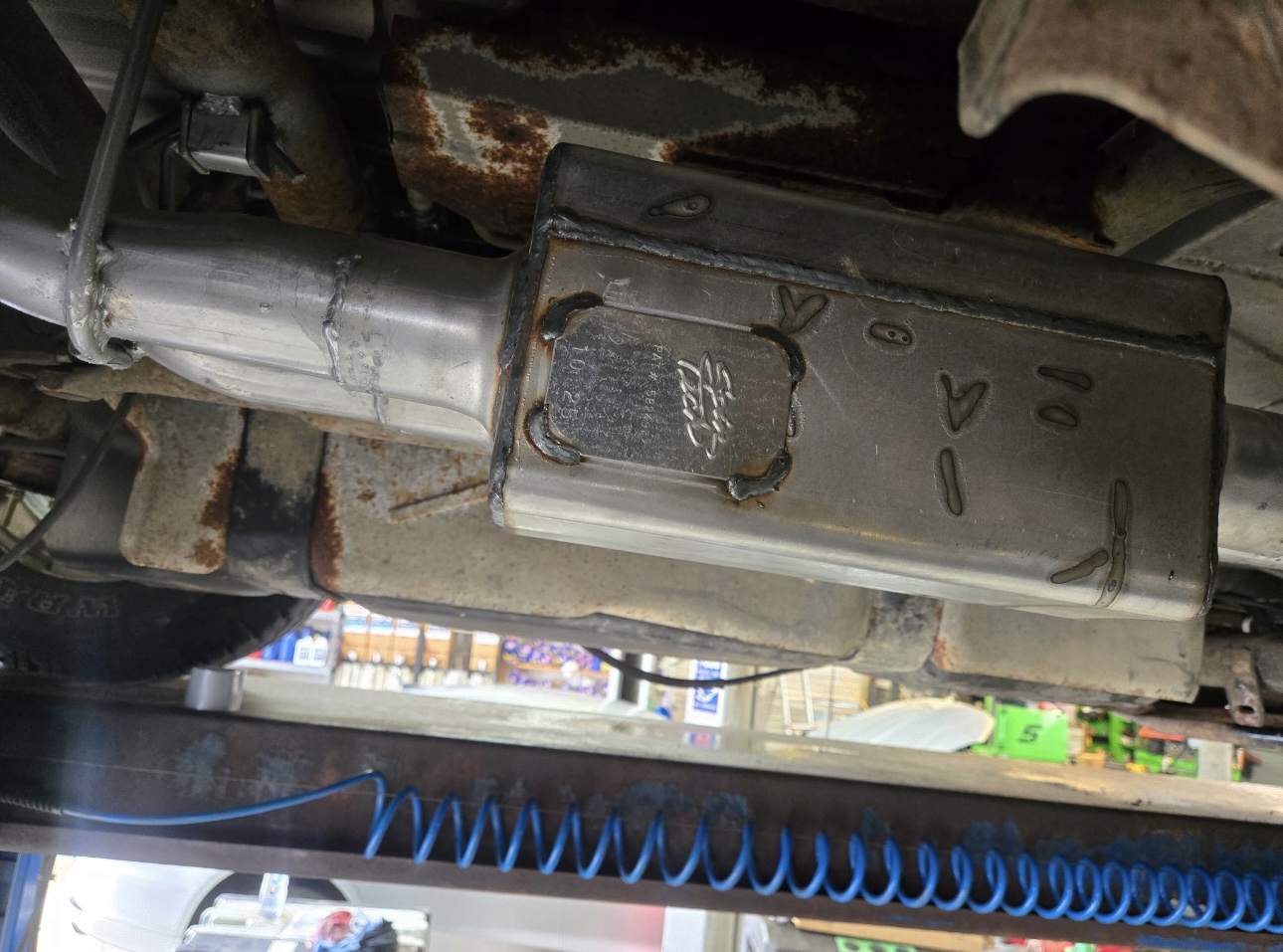 Muffler being inspected on the lift with shop in background