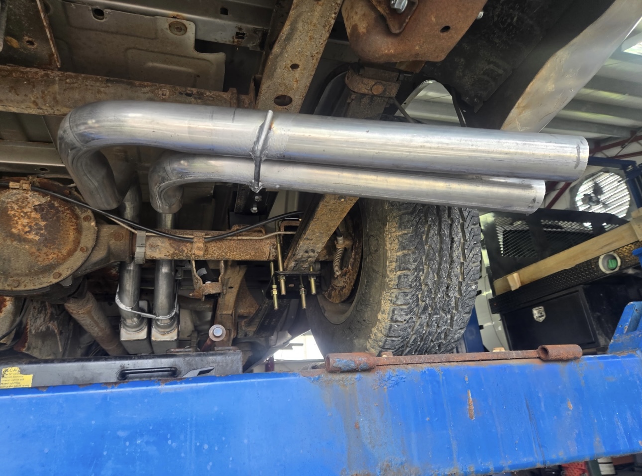 Custom exhaust pipe fabrication on a truck underside
