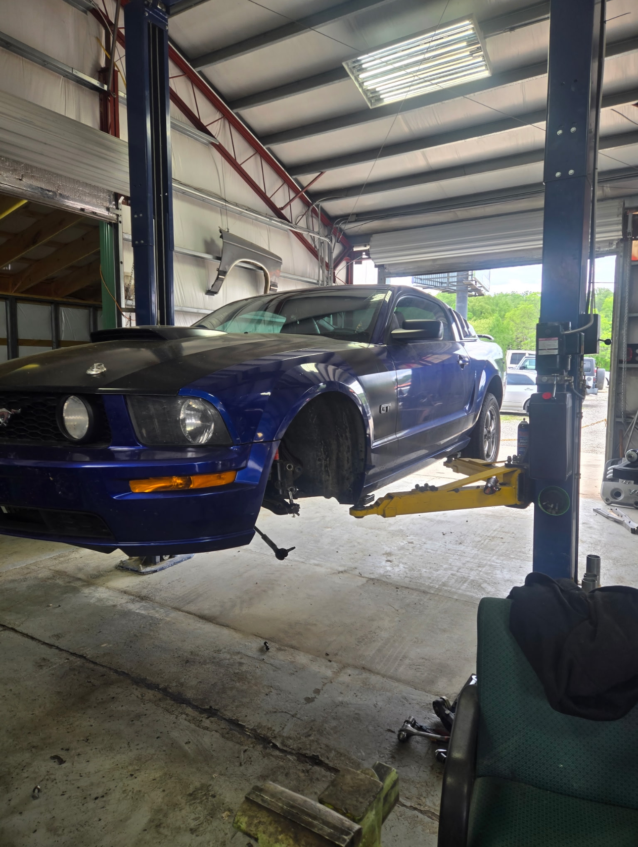 Blue Ford Mustang GT up on the lift in the shop bay