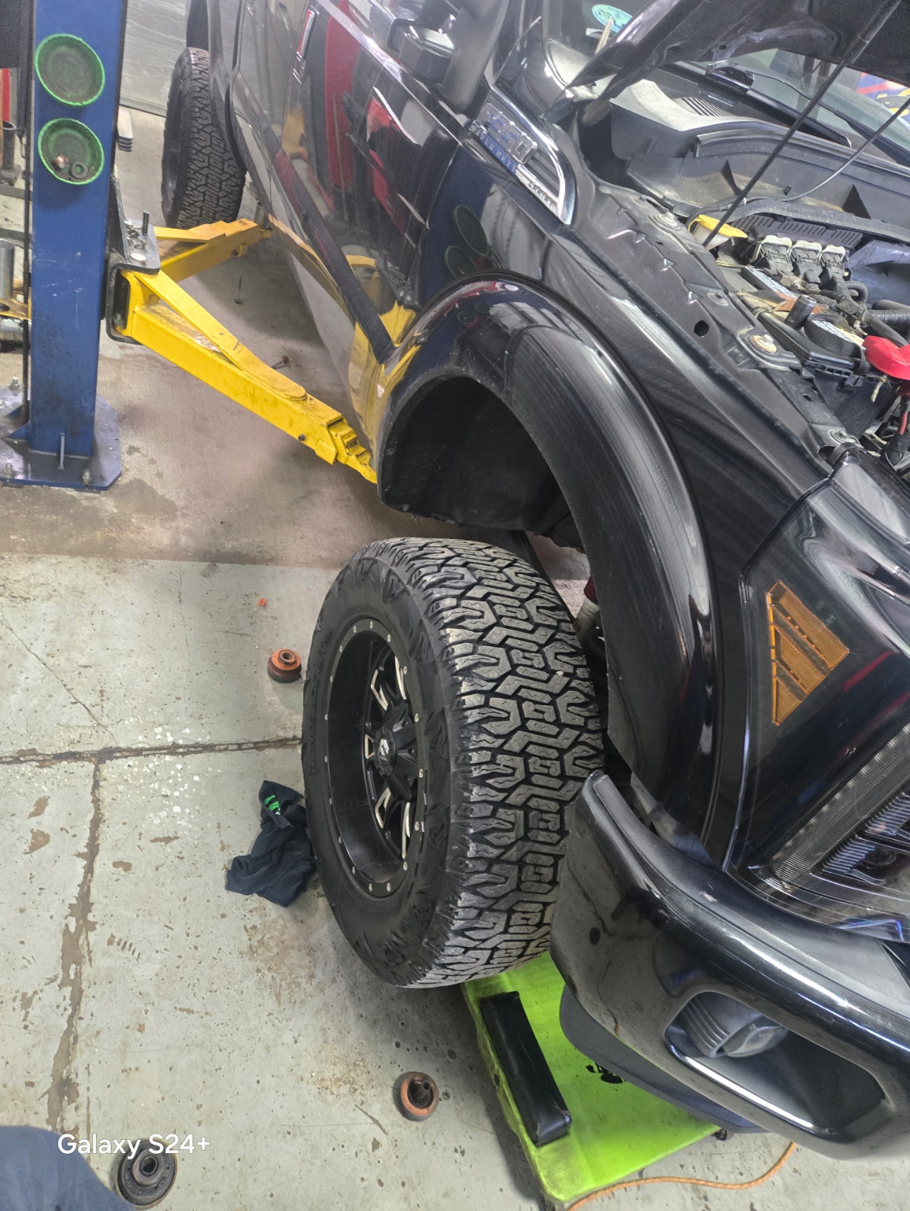 Black truck on the lift with wheel removed for tire service
